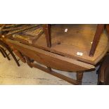 A pine drop-leaf circular table, raised on turned and ringed legs united by a stretcher,