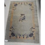 A Chinese rug, the central panel set with a single floral spray on a sage coloured ground,