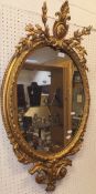 A 19th Century gilt oval wall mirror with acanthus and scrolling surmount with egg and scroll