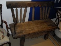 A rustic teak bench made from various parts with iron hand and arm rests