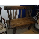 A rustic teak bench made from various parts with iron hand and arm rests