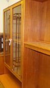 A modern teak lounge unit, nest of three tables, glass fronted cabinet, dining table,
