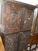 A 19th Century carved cupboard with carved pediment above two panelled cupboard doors with centre