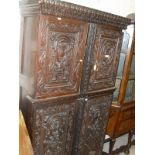 A 19th Century carved cupboard with carved pediment above two panelled cupboard doors with centre