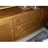A light elm Ercol sideboard with three central drawers flanked by cupboard doors