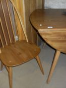 A light elm Ercol drop leaf dining table and four stick back dining chairs with elm seats,