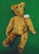 A gold plush wood wool filled bear in the manner of Steiff with glass eyes and worn felt pads