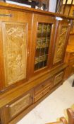 An oak dresser with central leaded glazed door flanked by two panels in simulated carved oak