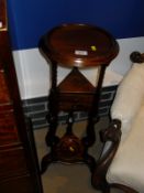 A mahogany wash-stand with circular turned top on three supports with two drawers united under tier