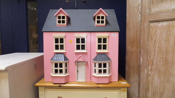 A modern pink painted dolls' house of traditional style,