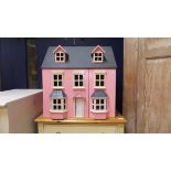 A modern pink painted dolls' house of traditional style,