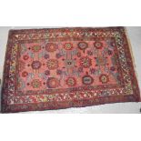 A Caucasian rug, the central panel set with stylised floral motifs on a pink ground,