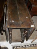 An oak gate leg table on bobbin turned supports to stretchered base
