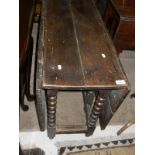 An oak gate leg table on bobbin turned supports to stretchered base