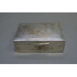 A silver cigarette box of plain rectangular form, with engine turned decoration to cover,