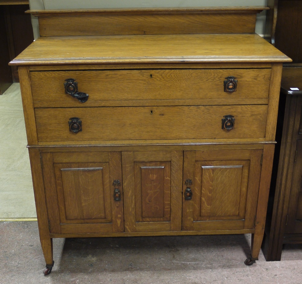 An early 20th century oak chest with two drawers, cupboards to the base,