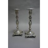 A pair of Continental silver candlesticks of baluster and foliate cast design on a square base with