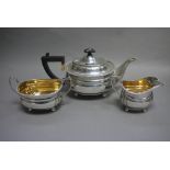 A three piece silver tea service of oblong form with gadroon rims, ebony handle and finial,