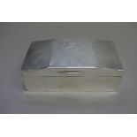 A silver cigarette box engraved with engine turned decoration to the canted cover with vacant