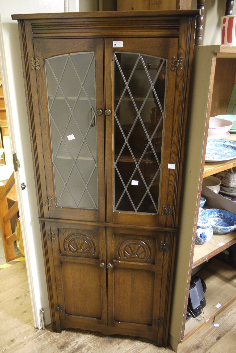 An oak floor standing corner cupboard, the upper glazed doors leaded, enclosing two shelves,