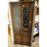 An oak floor standing corner cupboard, the upper glazed doors leaded, enclosing two shelves,