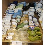 A collection of pottery and glass miniature shoes and boots including a tin glazed pair of slippers