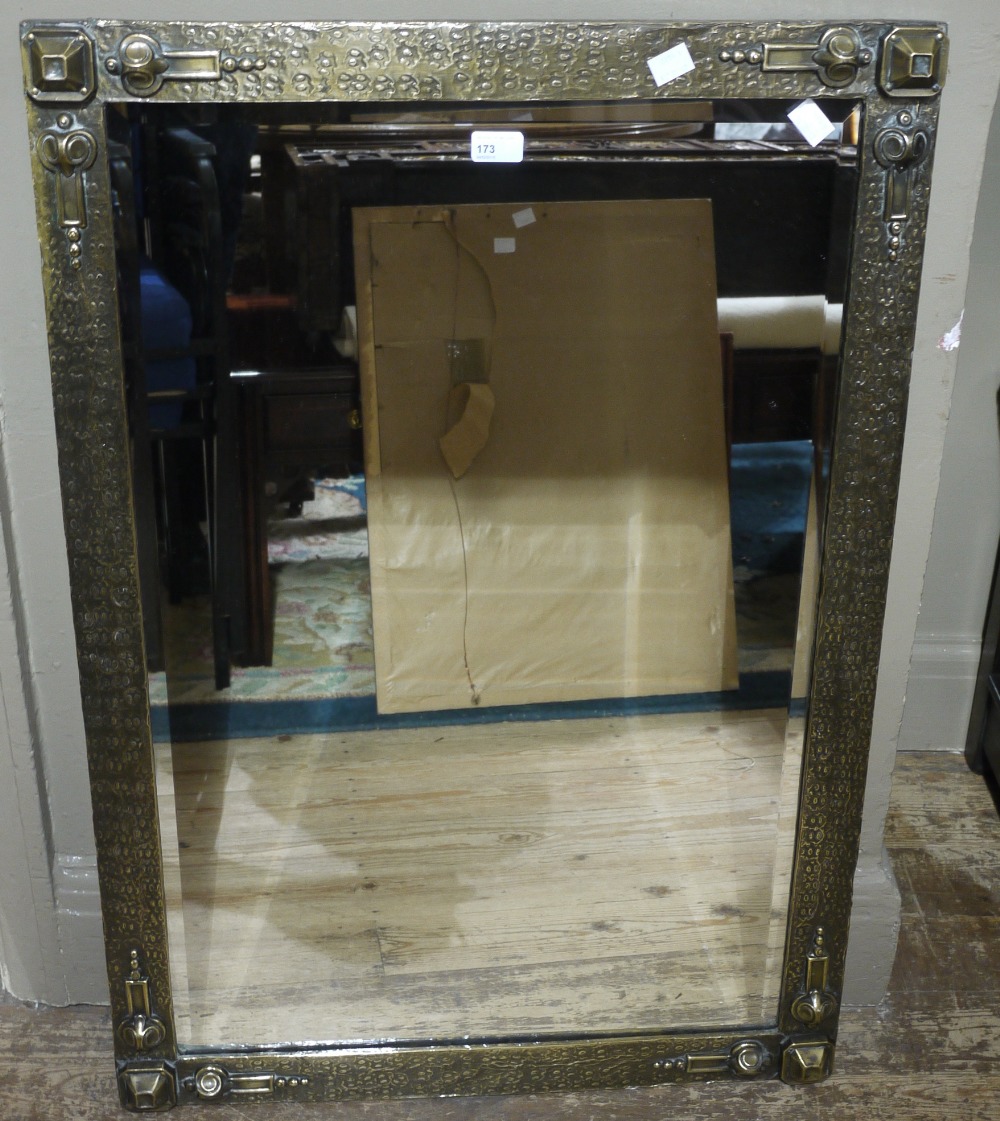 An Arts and Crafts style rectangular wall mirror with hammered and textured brass frame,