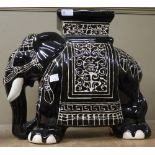 A black glazed oriental ceramic garden seat in the form of a ceremonial elephant