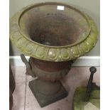 A cast iron campana shaped garden urn with double looped handles on a square base