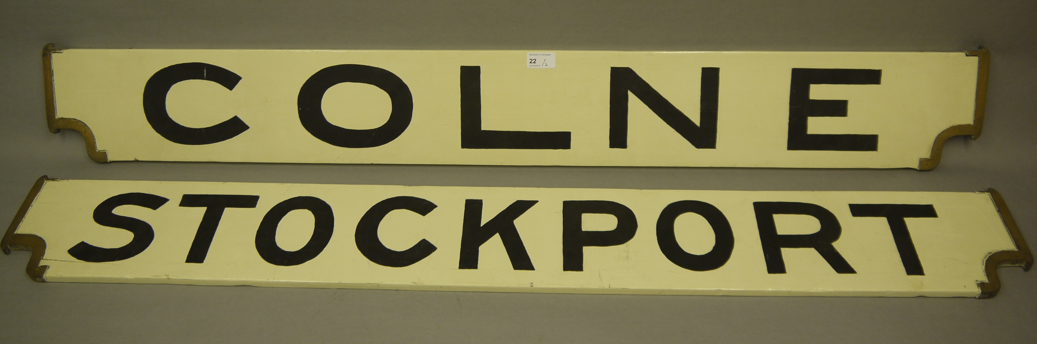 Two railway destination boards COLNE and STOCKPORT, in white with black lettering,