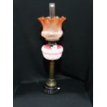 A Circular Based Brass Column Oil Lamp With Pink Tinted Reservoir And Etched Coloured Shade