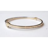 NINE CARAT GOLD TWO TONE BANGLE with safety clasp, approximately 5.