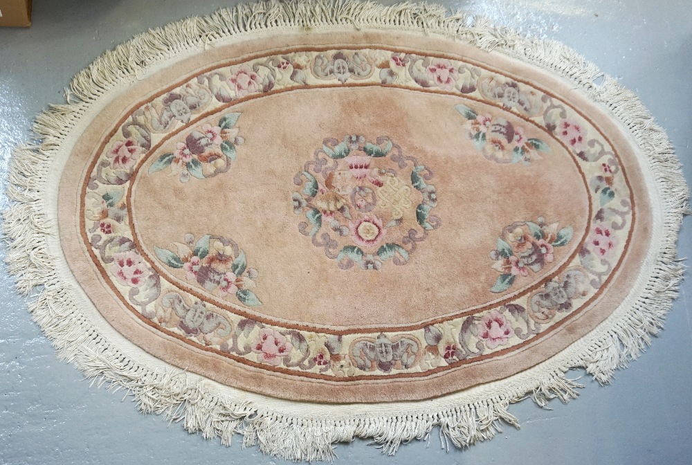 OVAL CHINESE WASH RUG the salmon pink ground decorated with flowers, with a fringed border,