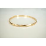 EIGHTEEN CARAT GOLD BANGLE with faceted decoration,