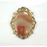 ATTRACTIVE AGATE SET BROOCH in pierced and scroll decorated unmarked gold mount, approximately 4.