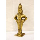 GILT BRASS BUDDHIST DEITY possibly Indonesian, wearing traditional dress with his arms on his hips,