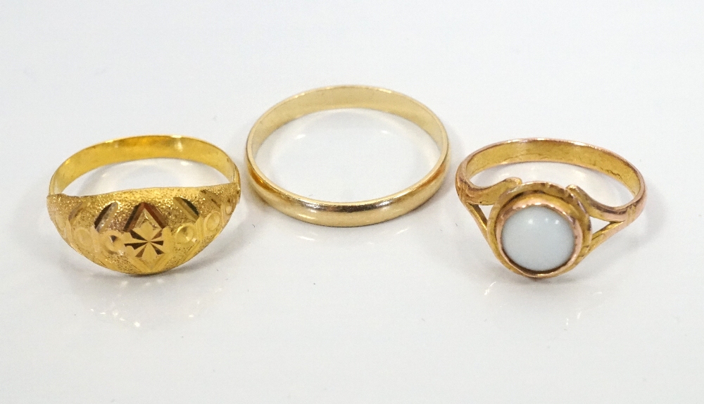 TEN CARAT GOLD WEDDING BAND together with two unmarked gold rings, one set with cabochon stone,