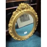 A CONTINENTAL GILTWOOD AND GESSO MIRROR the oval plate within a flowerhead and foliate frame 48cm x