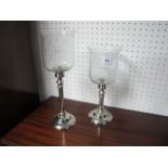 TWO GRADUATED CANDLE HOLDERS each with a cylindrical turned column raised on a circular spreading