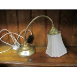 A BRASS READING LAMP with adjustable arm and frosted glass shade