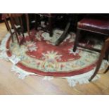 A CIRCULAR WOOL RUG the orange ground with cream border and decorated overall with foliate sprays