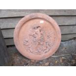 A TERRACOTTA CIRCULAR CHARGER the rim decorated with foliate and beaded border centred by a