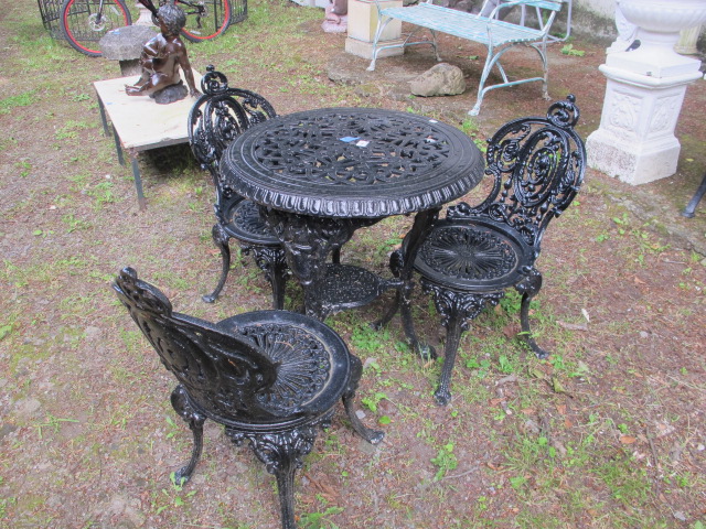 A VICTORIAN STYLE THREE PIECE BLACK PAINTED METAL GARDEN SUITE comprising of a table with circular