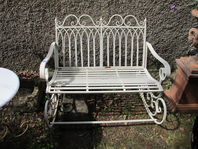 A GREEN PAINTED GOTHIC STYLE WROUGHT IRON ROCKING GARDEN BENCH the rectangular open back headed by