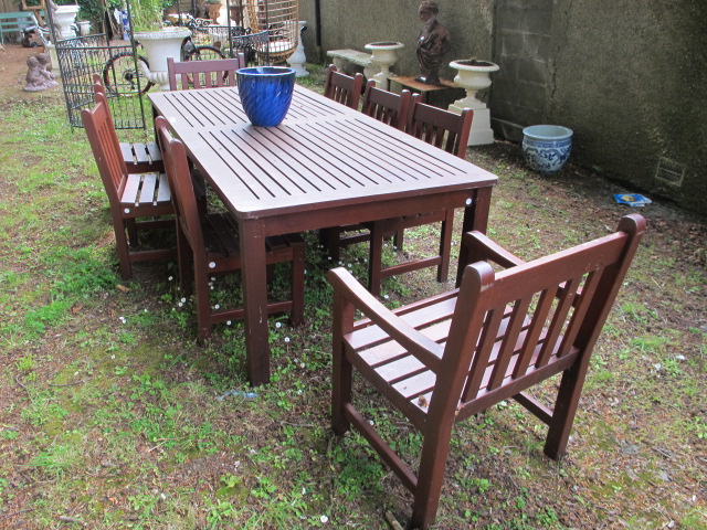 A NINE PIECE WOODEN GARDEN SUITE comprising of a rectangular table with slatted top raised on