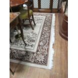 A RECTANGULAR WOOL RUG the cream ground with brown border and decorated overall with foliate filled