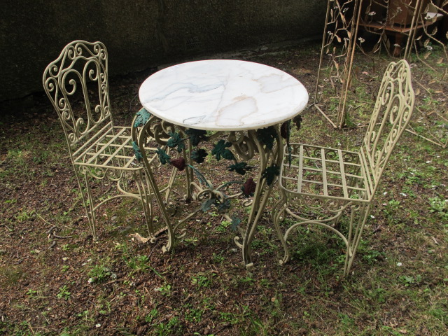 A THREE PIECE GARDEN SUITE COMPRISING OF A CIRCULAR MARBLE TOP TABLE raised on pierce and cabriole