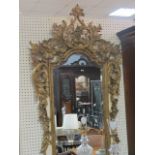 A GILT AND CREAM PAINTED CONTINENTAL STYLE OVERMANTEL MIRROR the foliate cartouche above a shield