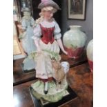 A VICTORIAN CHINA FIGURE modelled as a young girl shown standing