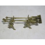 A BRASS FIRE SET comprising a pair of fire dogs, tongs,